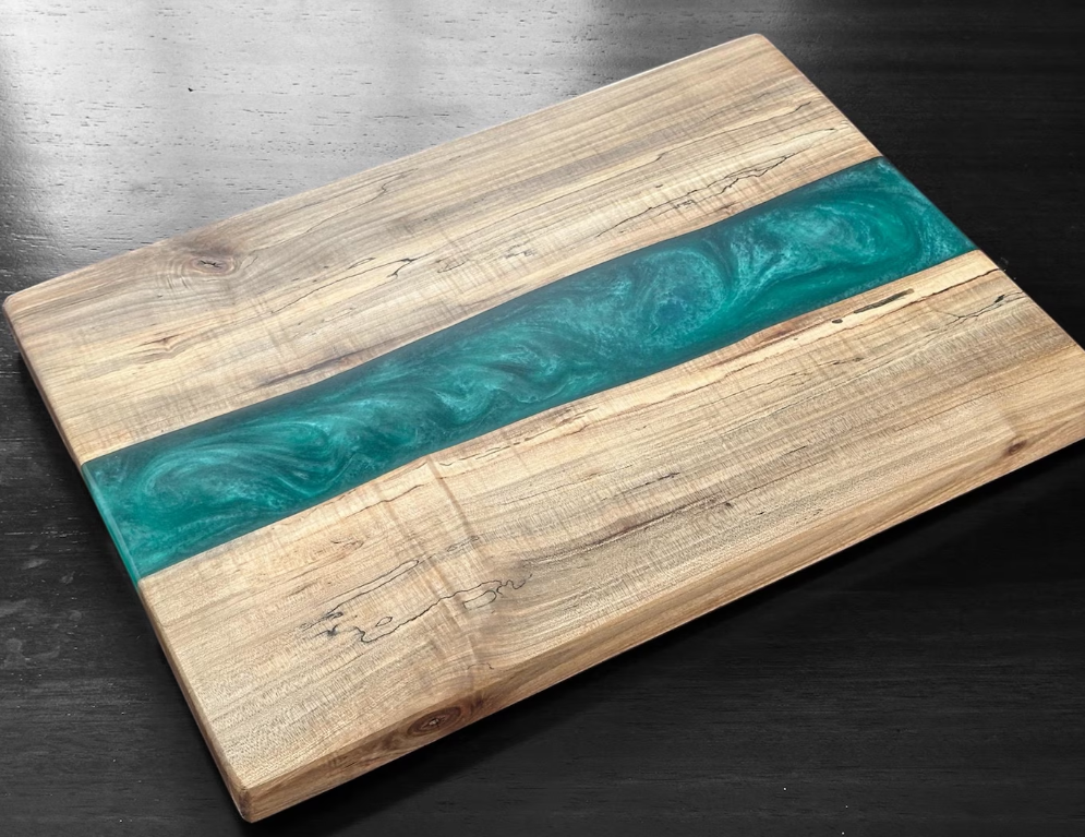 Liquid epoxy being poured over maple wood